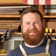 As seen on Home Town, Ben Napier (C) works to finish putting together a dovetail wood drawer in their workshop located in Laurel, MS. Erin and Ben visit estate sales and flea markets looking for antique cotton flags to carry in their shop, the Laurel Mercantile Co. The flag in this photo hangs in their shop as a reminder of why American-made craftsmanship still matters. (workshop, portrait)